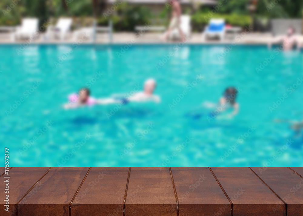 Empty wooden floor on pool. Tourists family swimming blurred background