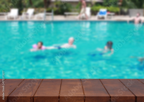 Empty wooden floor on pool. Tourists family swimming blurred background