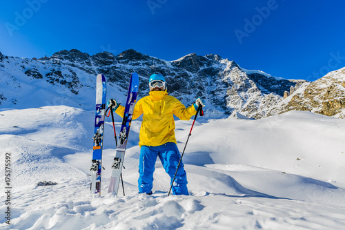 Fototapeta Mountaineer backcountry ski walking up along a snowy ridge with skis in the backpack. In background blue sky and shiny sun and Zebru, Ortler in South Tirol, Italy.  Adventure winter extreme sport. 