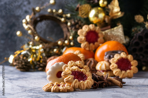 A set of Christmas decorations with tangerines, cookies over a stone background.