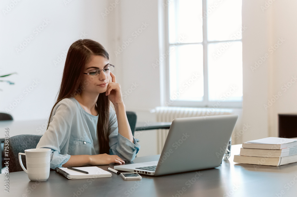 Attractive brunette woman writer sitting at the table and writing on the laptop computer. Attractive brunette woman writer sitting at the table and writing on the laptop computer.