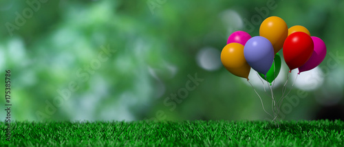 Group of colorful balloons on green grass and abstract background. 3d illustration