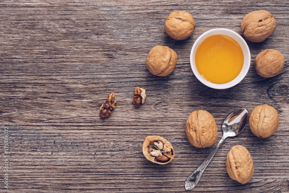 A bowl of honey and walnuts on a wooden brown table. View from above. A bowl of honey and walnuts on a wooden brown table. View from above.