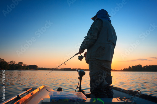 A fisherman fishing in a lake at sunset