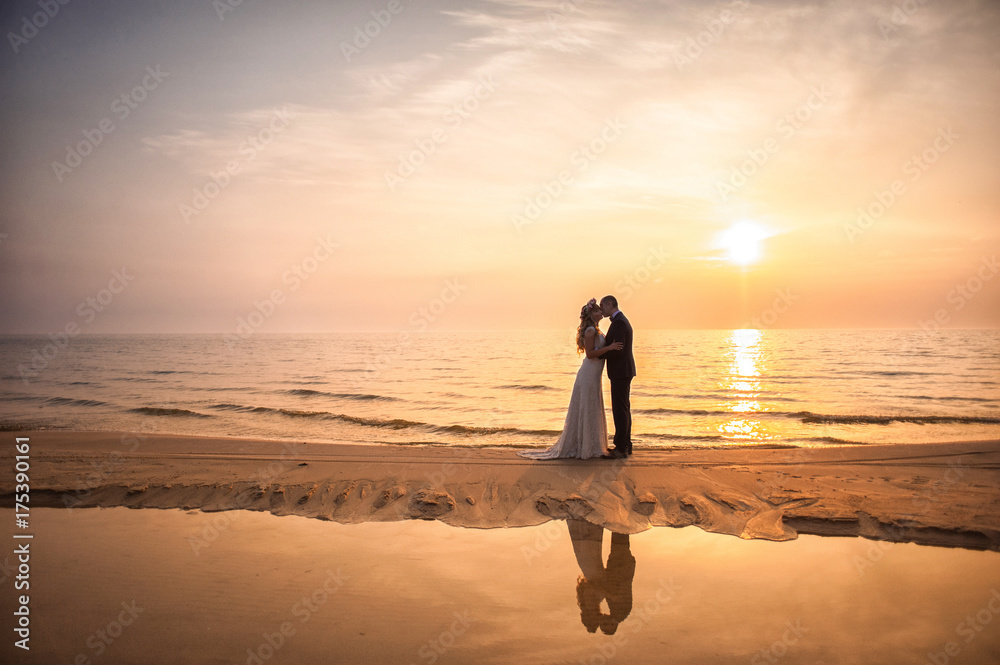Εκτύπωση καμβά Bride and groom, newlyweds, honeymoon on the beach sunset sun