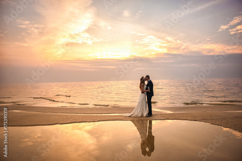Tableau sur toile Bride and groom, newlyweds, honeymoon on the beach sunset sun