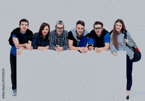 Full length portrait of confident college students displaying blank billboard against white background