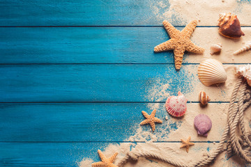 beach scene concept with sea shells and starfish on a blue wooden background
