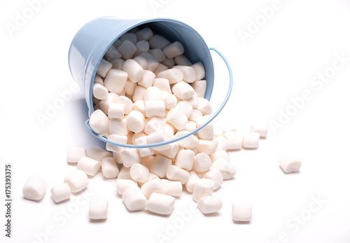 Fluffy white marshmallow macro in blue bucket isolated over white background. Heap of white marshmallows. Food background. Copy space. photo