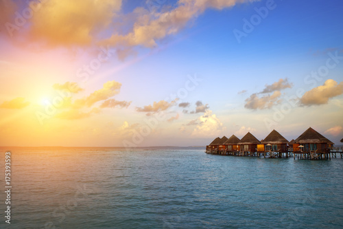 houses over the transparent quiet sea water  on a sunset. Maldives..