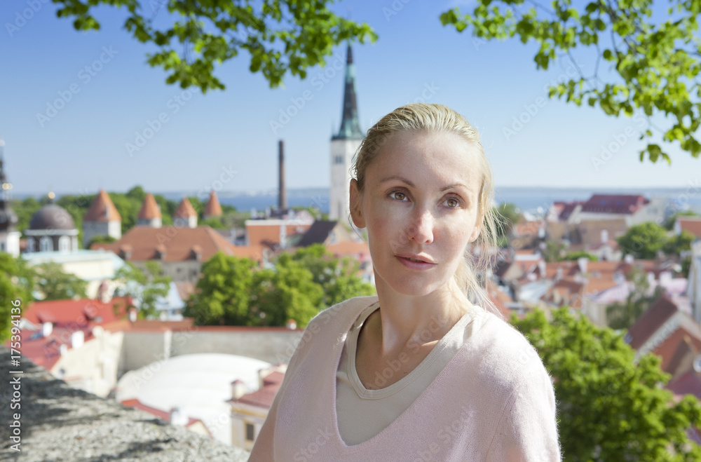 The young attractive woman admires roofs of houses of the Old city from an observation deck. Tallinn. Estonia.