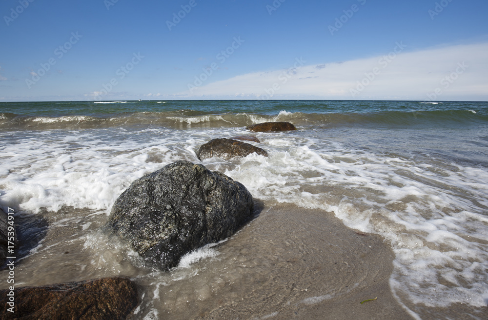 sunny day with Waves hitting stones on the beach
