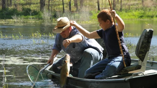 Father and son reel in catfish on lake
