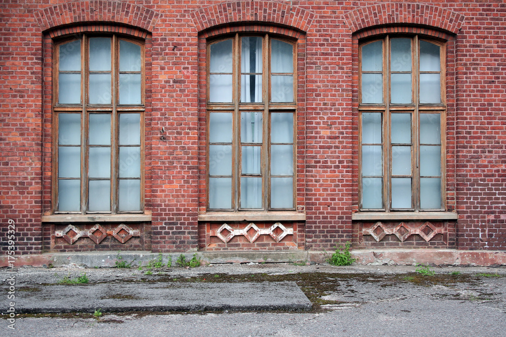 Three antique windows in the wall of red brick