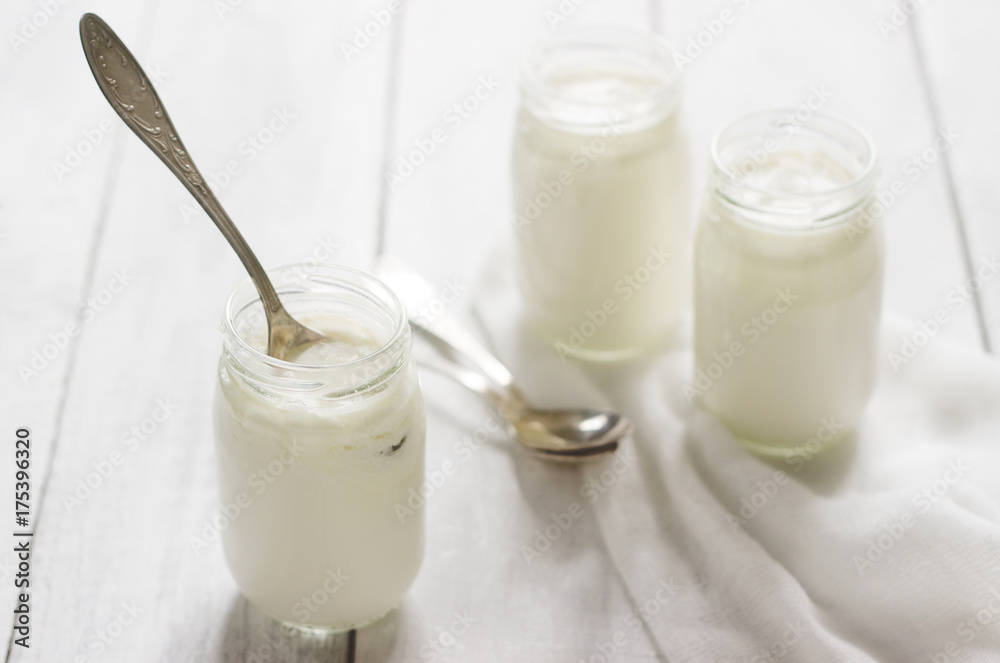 Homemade yogurt in a glass jar on a wooden table. Rustic style, selective focus. Homemade yogurt in a glass jar on a wooden table. Rustic style, selective focus.