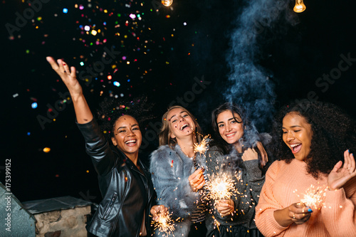 Group of young women celebrating new years eve outdoors, throwing confetti