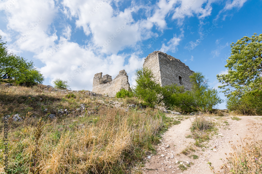 Castle ruin on the hill, blue sky and white clouds, path on the ground