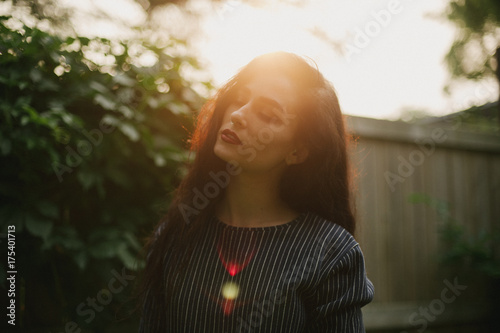 Pretty dark haired woman in alleyway with sunburst light at sunset photo