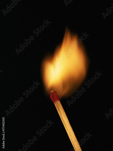 Single burning match on black background