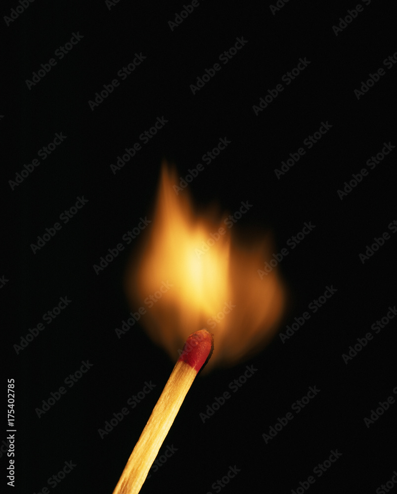Single burning match on black background