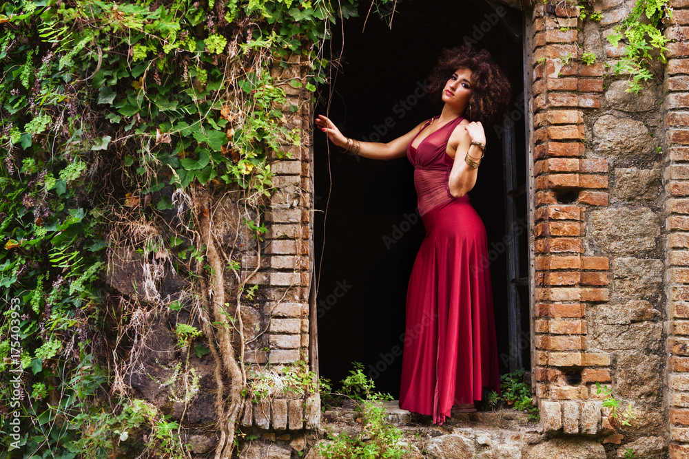 Fototapeta premium Bella ragazza con abito rosso in un castello abbandonato