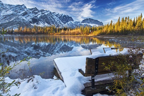 Park Bench on Many Springs lake in Bow Provincial Park at foothills of Rocky Mountains  Alberta  Canada  after early October snowfall with Distant Snowy Mountain Tops Landscape View