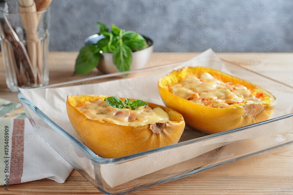 Baking dish with halves of stuffed spaghetti squash on table