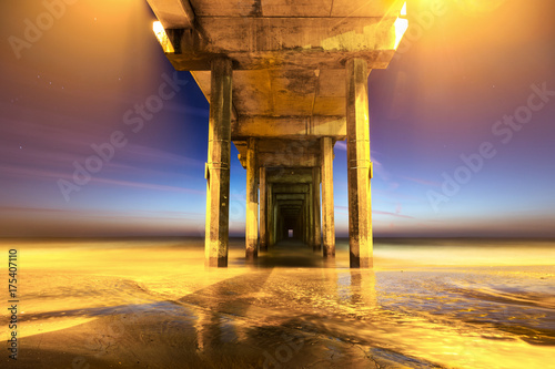 Scripps Pier in La Jolla Shores near UCSD in San Diego California after sunset.  Yellow cast created by lamps on top of pier provide surreal lighting effect photo