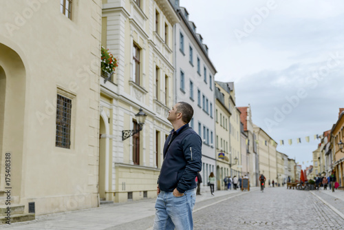 young tourist looks at the sights of a European city, raising his head high