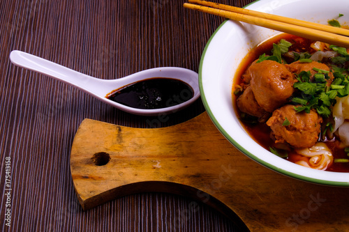 Indonesian famous foodstreet bakso / meatballs in a white bowl served with kuey teow on the table. photo