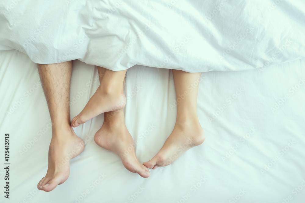 Closeup Feet of couple man and woman making love or sex on bed under blanket at hotel, home, sweet valentine concept. Closeup Feet of couple man and woman making love or sex on bed under blanket at hotel, home, sweet valentine concept.