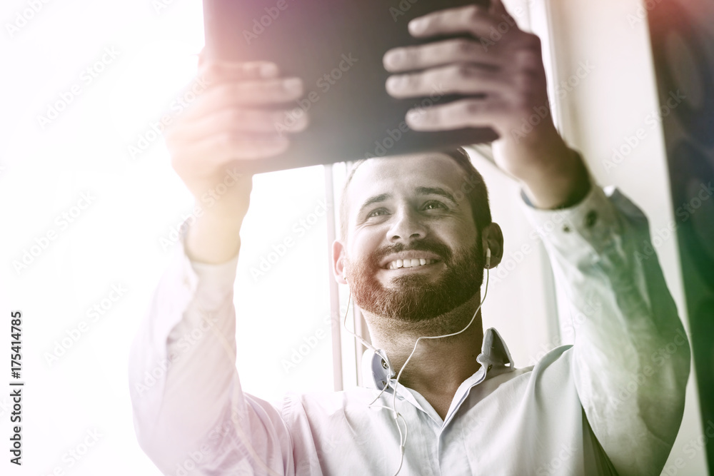 Naklejka premium smiling businessman with digital tablet and earphones calling with video conference