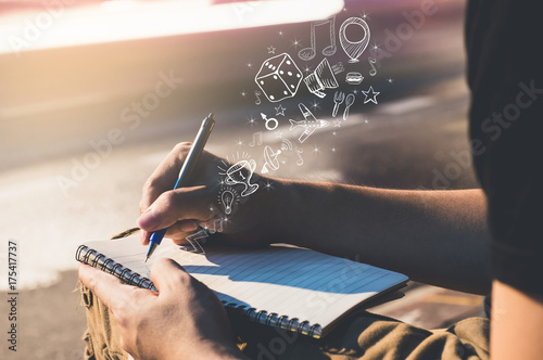Man hand with pen writing on notebook. The pen is on the roadside. with icons and symbols