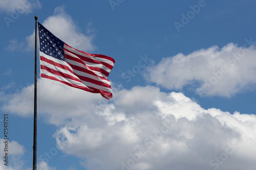 Flag of United States of America (USA) waving in the wind with blue sky and clouds on background