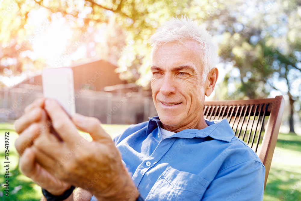 LoMature man outdoors using mobile phone