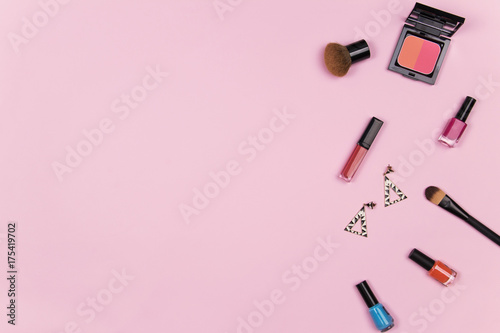 Beauty blog fashion concept. Female pink styled : cosmetics, lipstick, nail polish, brush on, earring on pink background. Flat lay, top view trendy feminine background.