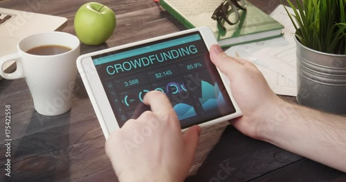 Monitoring crowdfunding data using tablet computer at desk photo
