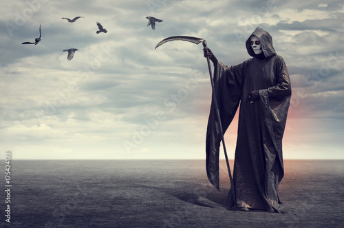 A horrible Death with a scythe on the background of desert landscape with flying crows. photo