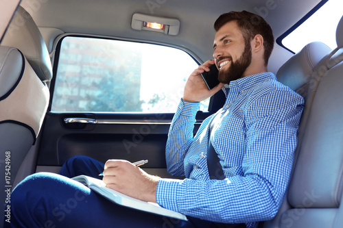 Handsome man with smartphone on backseat of car © Africa Studio
