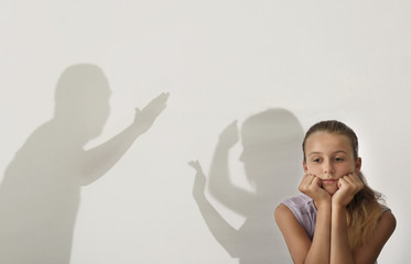 Little girl and silhouettes of quarreling parents on background. Domestic violence concept