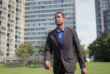 Modern African American business man in suits walking through the park,  looking sharp and confident