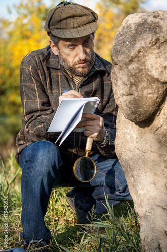 scientist and historian, describes sitting stone sculpture on mound photo