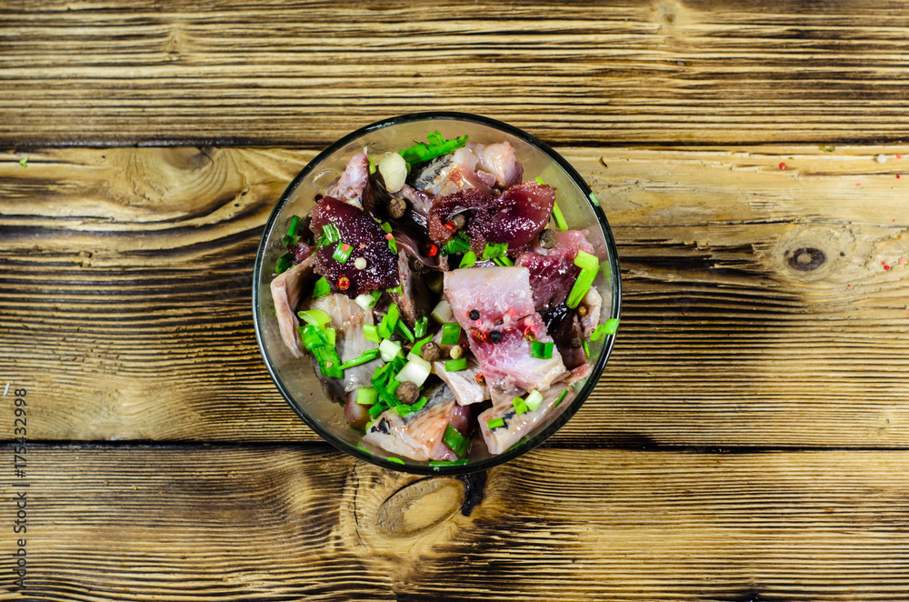 Herring with spices in glass bowl on wooden table. Top view Herring with spices in glass bowl on wooden table. Top view