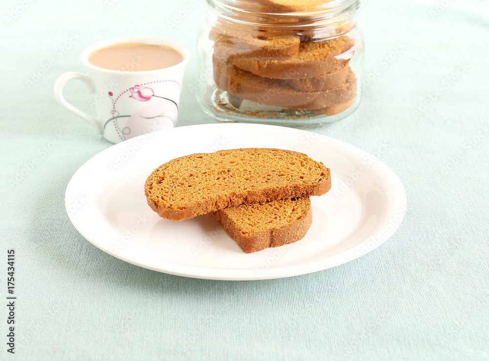 Rusk, a popular, crunchy and crispy biscuit, and tea, on a plate. Rusk, a popular, crunchy and crispy biscuit, and tea, on a plate.
