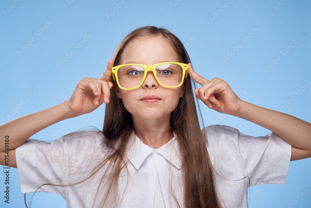 a little girl with long hair in a white shirt and wearing yellow glasses