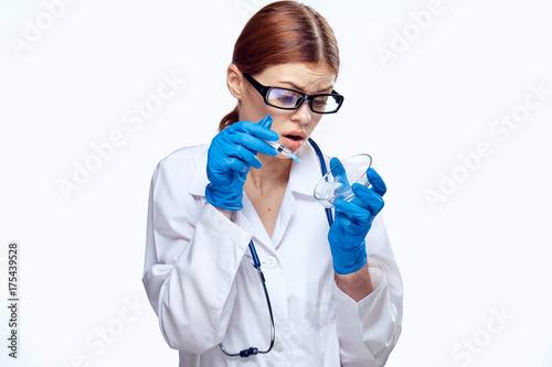 a woman in glasses holds a syringe and a petri dish, a doctor, a scientist