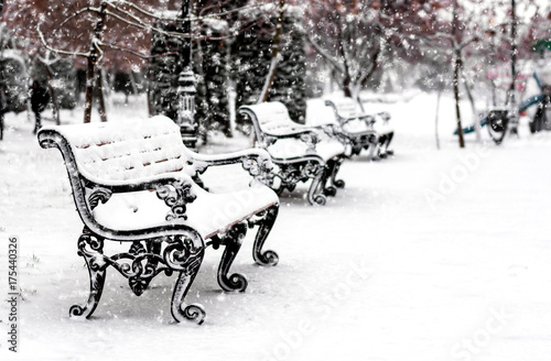 Empty bench in snowly city park at winter snowfall season © Vastram