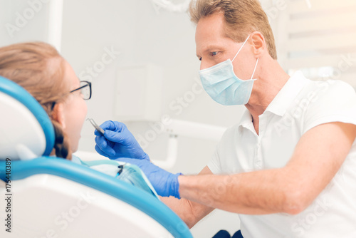 Serious dental professional treating teeth of child