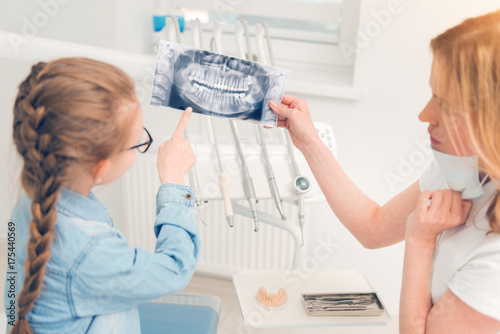 Dentist professional showing her little patient scan of jaws
