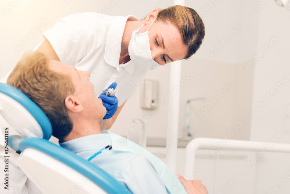 Focused female dentist treating teeth of male patient Focused female dentist treating teeth of male patient
